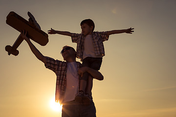 Image showing Father and son playing with cardboard toy airplane in the park a