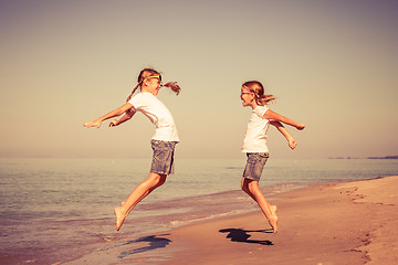 Image showing Two sisters playing on the beach at the day time.