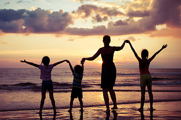 Image showing Mother and children playing on the beach at the sunset time.