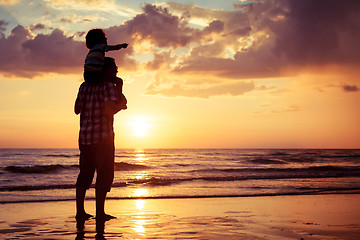 Image showing Father and son playing on the beach at the sunset time.