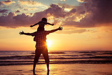 Image showing Father and son playing on the beach at the sunset time.