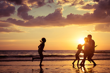 Image showing Father and children playing on the beach at the sunset time.