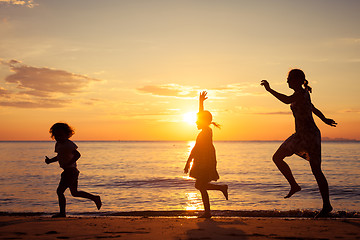 Image showing Mother and children playing on the beach at the sunset time.