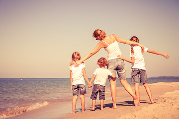 Image showing Mother and  children playing on the beach.