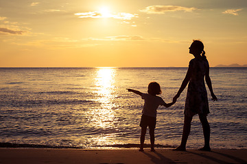 Image showing Mother and son playing on the beach at the sunset time.