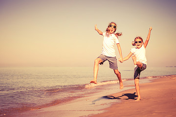 Image showing Two sisters playing on the beach at the day time.