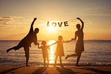 Image showing Happy family standing on the beach at the sunset time.