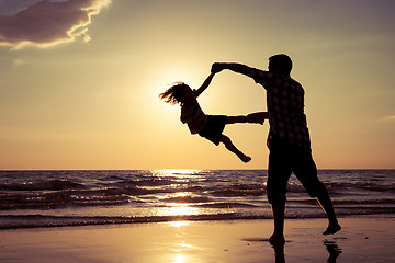 Image showing Father and son playing on the beach at the sunset time.