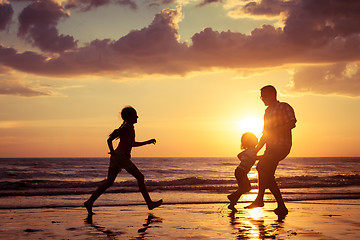 Image showing Father and children playing on the beach at the sunset time.