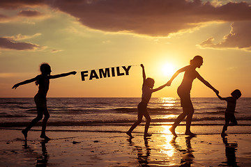 Image showing Mother and children playing on the beach at the sunset time.