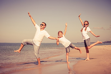 Image showing Father and daughters playing on the beach at the day time.