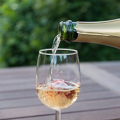 Image showing Pouring champagne in a glass in a garden