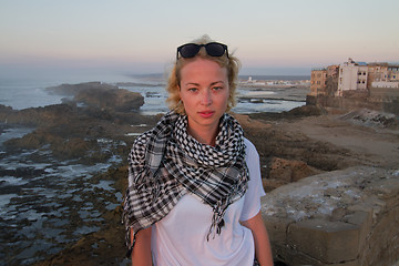 Image showing Female traveler standing on city fortress wall of Essaouira, Morocco in sunset.