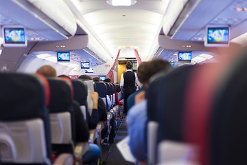 Image showing Interior of commercial airplane with passengers on seats during flight.