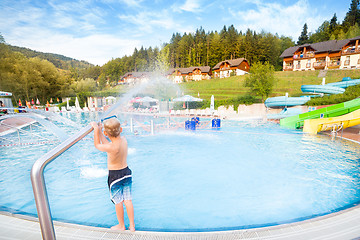 Image showing Child playing with water making splashes at the poolside.