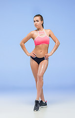 Image showing Muscular young woman athlete posing at studio