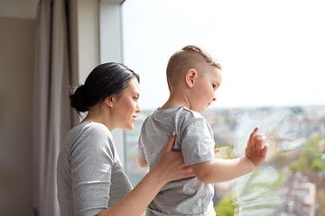 Image showing mother and son looking through window at home