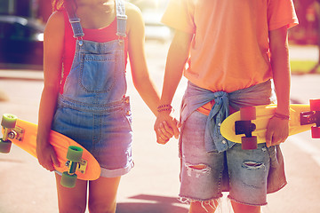 Image showing close up of young couple with skateboards in city