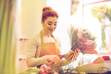 Image showing smiling florist woman making bunch at flower shop