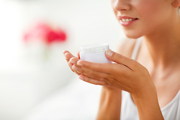 Image showing close up of happy woman holding and smelling cream