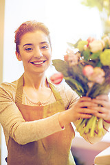 Image showing smiling florist woman making bunch at flower shop