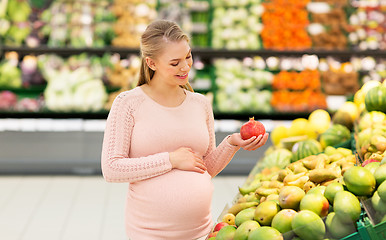 Image showing happy pregnant woman with pomegranate at grocery