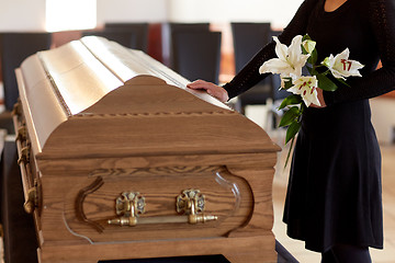 Image showing woman with lily flowers and coffin at funeral