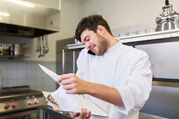 Image showing chef cook calling on smartphone at restaurant kitchen