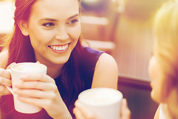 Image showing smiling young women with coffee cups at cafe