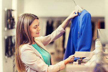 Image showing happy young woman choosing clothes in mall