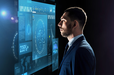 Image showing businessman looking at virtual screen over black