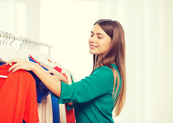 Image showing happy woman choosing clothes at home wardrobe