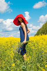 Image showing happy woman in a red hat with a bouquet of wildflowers