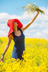 Image showing joyful woman in a red hat with a bouquet of wild flowers