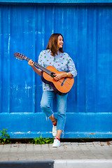 Image showing Beautiful smiling woman in jeans playing guitar 