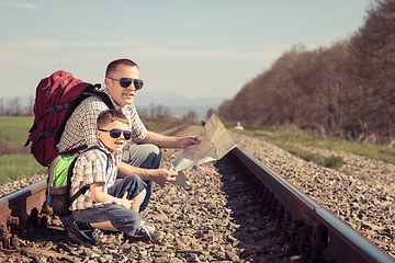 Image showing Father and son walking on the railway at the day time.