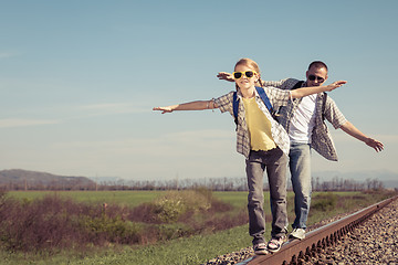 Image showing Father and daughter walking on the railway at the day time.