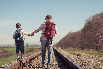 Image showing Father and son walking on the railway at the day time.