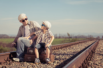 Image showing Father and son walking on the railway at the day time. 