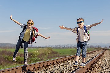 Image showing Happy brother and sister walking on the railway at the day time.