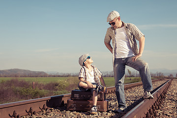 Image showing Father and son walking on the railway at the day time.