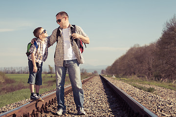 Image showing Father and son walking on the railway at the day time.