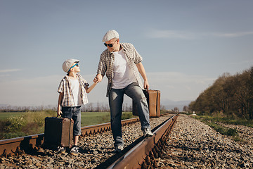 Image showing Father and son walking on the railway at the day time.