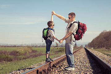 Image showing Father and son walking on the railway at the day time.