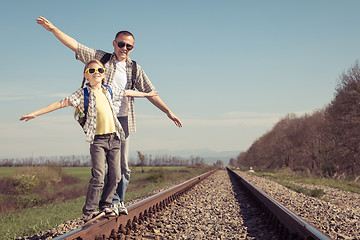 Image showing Father and daughter walking on the railway at the day time.