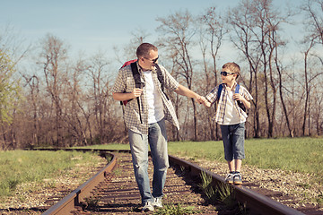 Image showing Father and son walking on the railway at the day time.