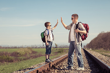 Image showing Father and son walking on the railway at the day time.