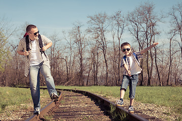 Image showing Father and son walking on the railway at the day time.