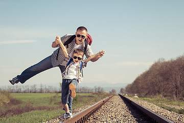 Image showing Father and son walking on the railway at the day time.