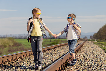 Image showing Happy brother and sister walking on the railway at the day time.